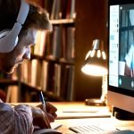 Male student wearing headphones video conference calling watching webinar.