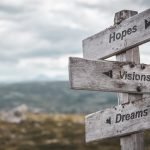 hopes visions dreams text engraved on wooden signpost outdoors in nature. Panorama format.